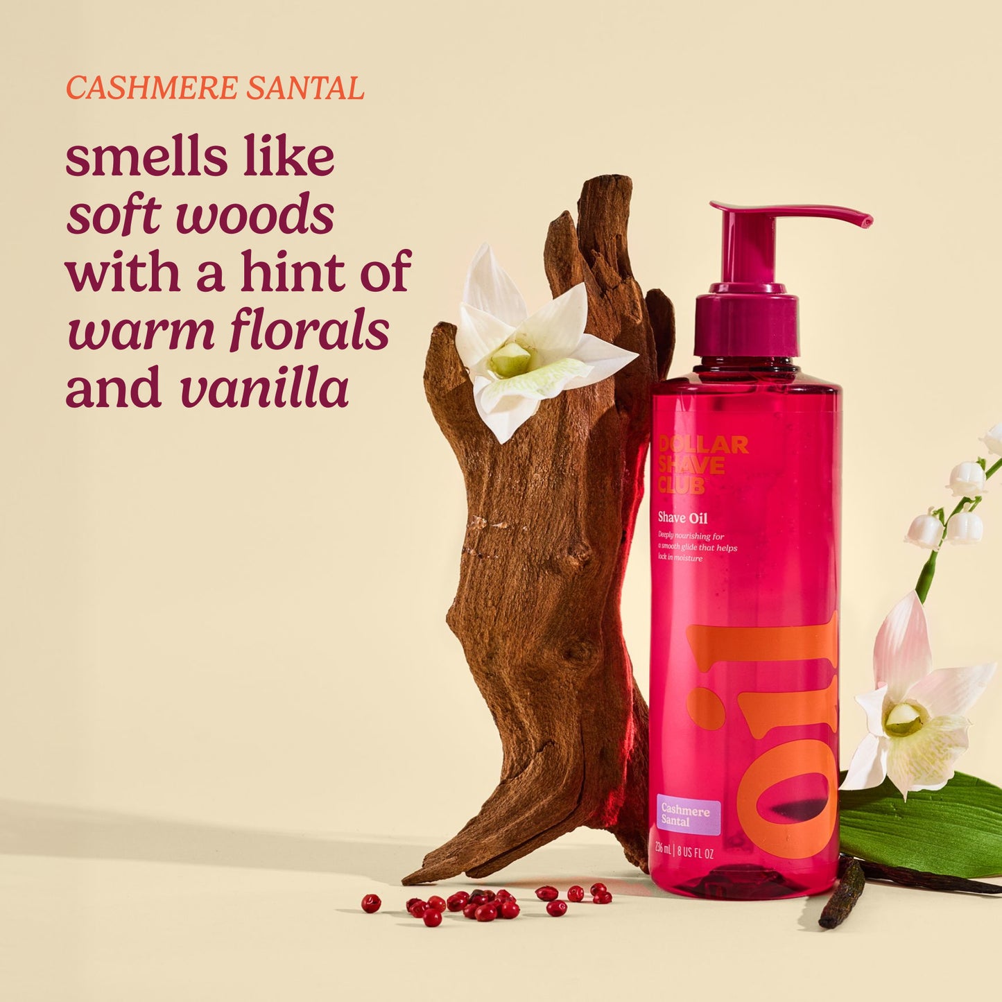 Pink bottle with pump dispenser next to wooden element and flowers on beige background