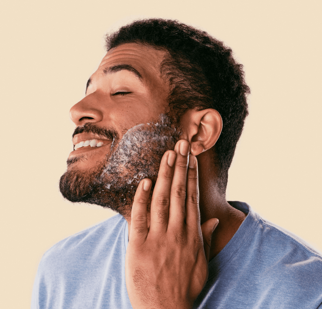 Man rubbing shaving cream on his face while smiling.