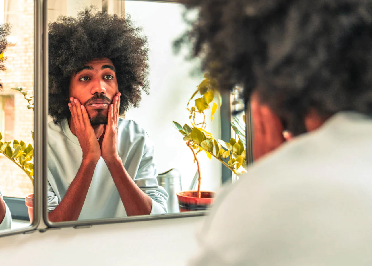 Man looking in mirror at facial hair.