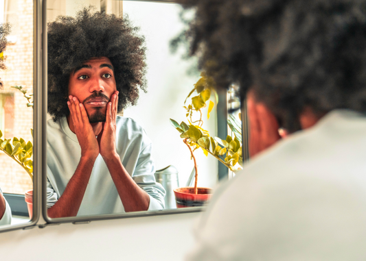 Man looking at shaved face and beard in mirror.