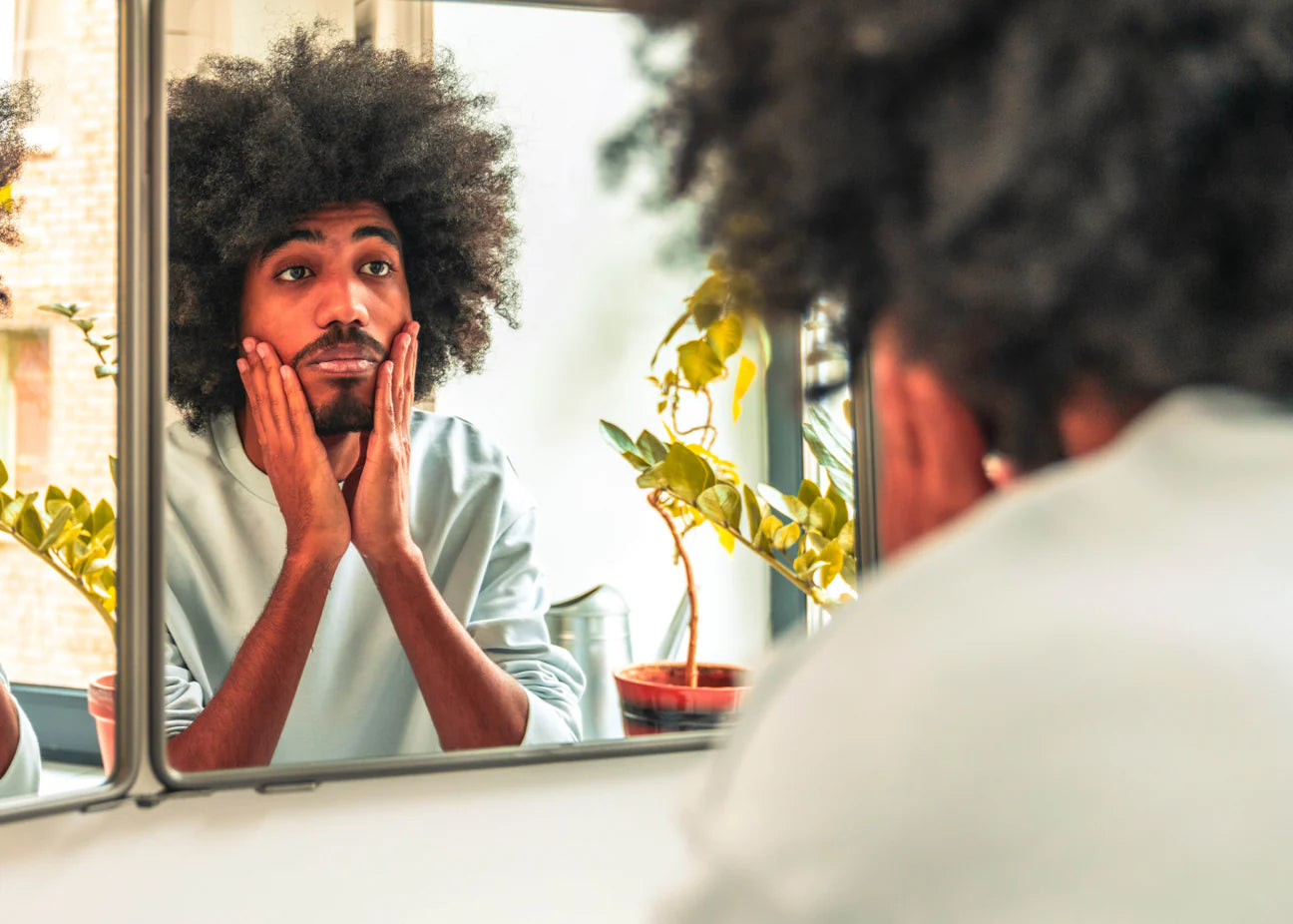 Man looking in mirror at beard.