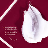 Body balm being applied to skin with a maroon background