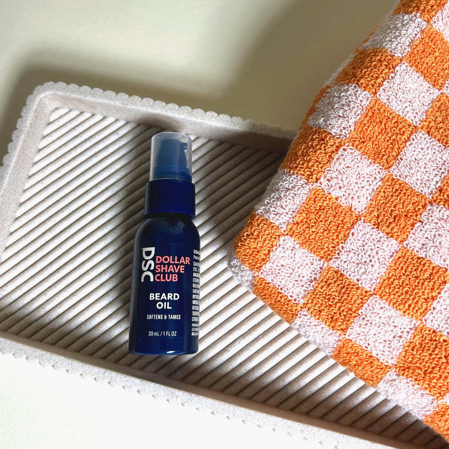 Image of Beard Oil on tray with orange checkered towel.