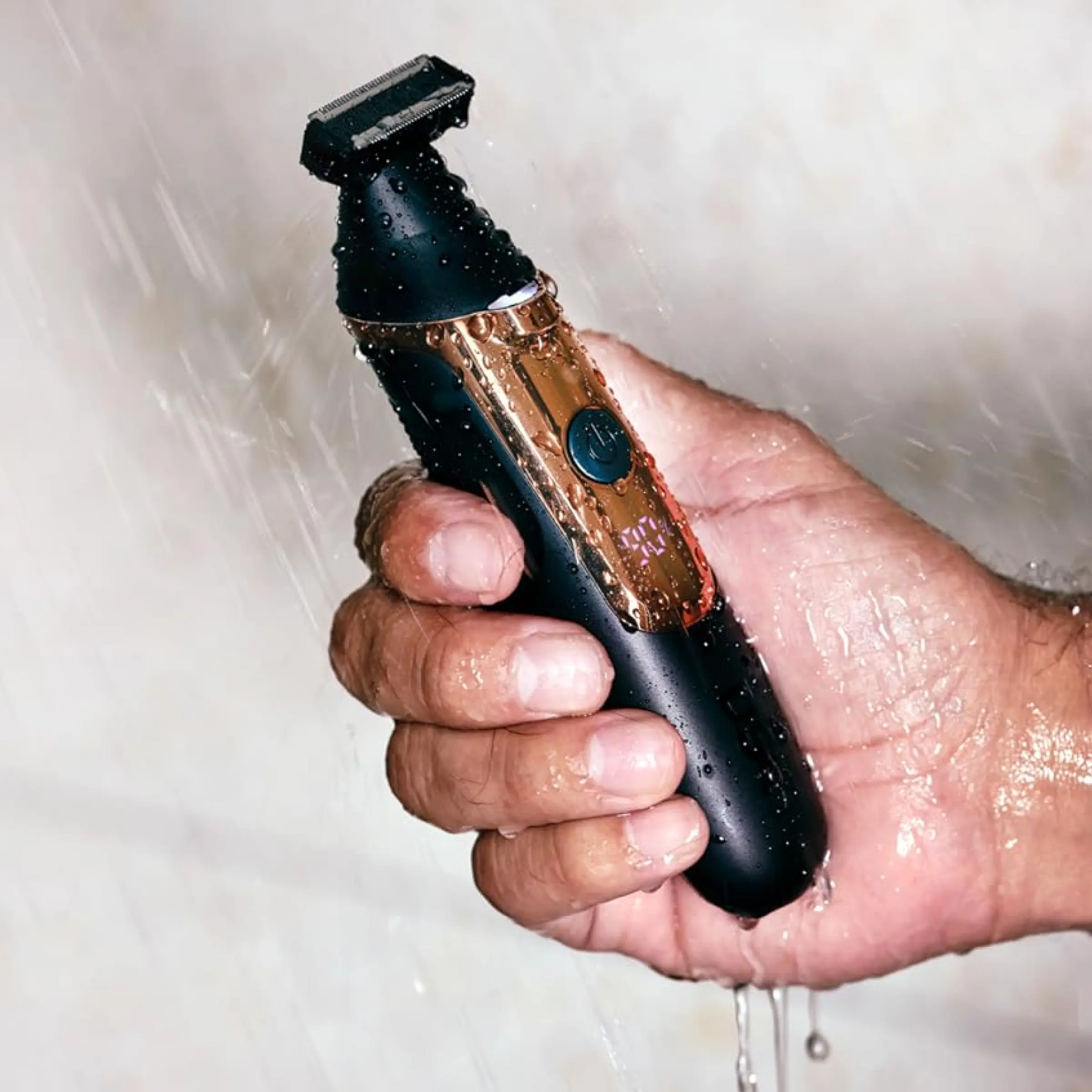 Man holding Double Header Electric Trimmer under running water.