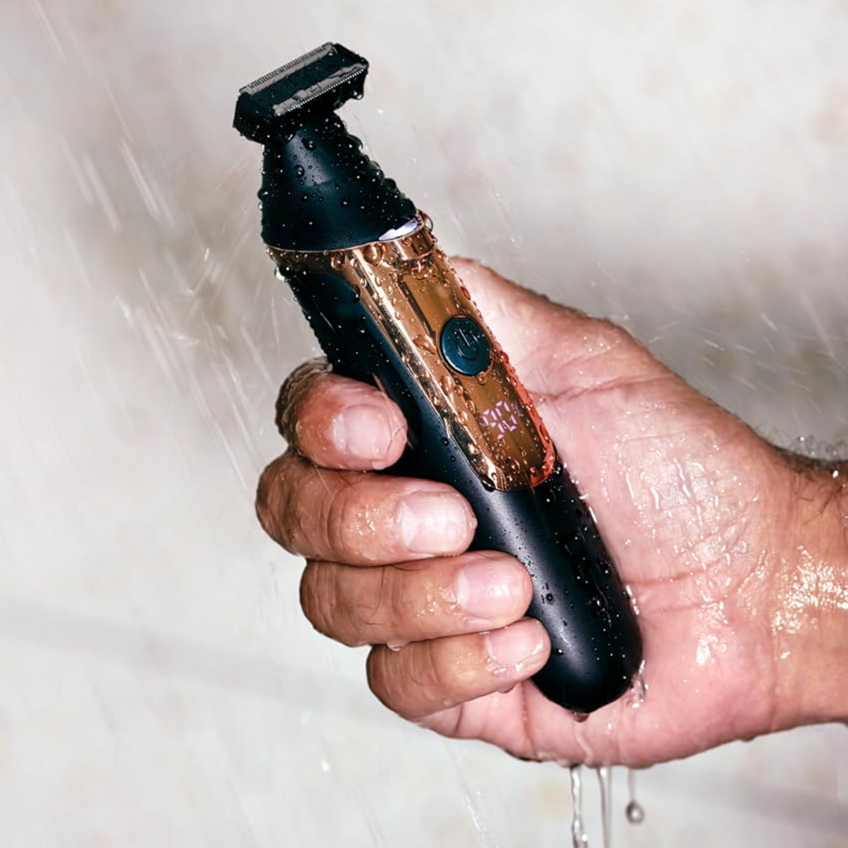 Man holding Double Header Electric Trimmer under running water.