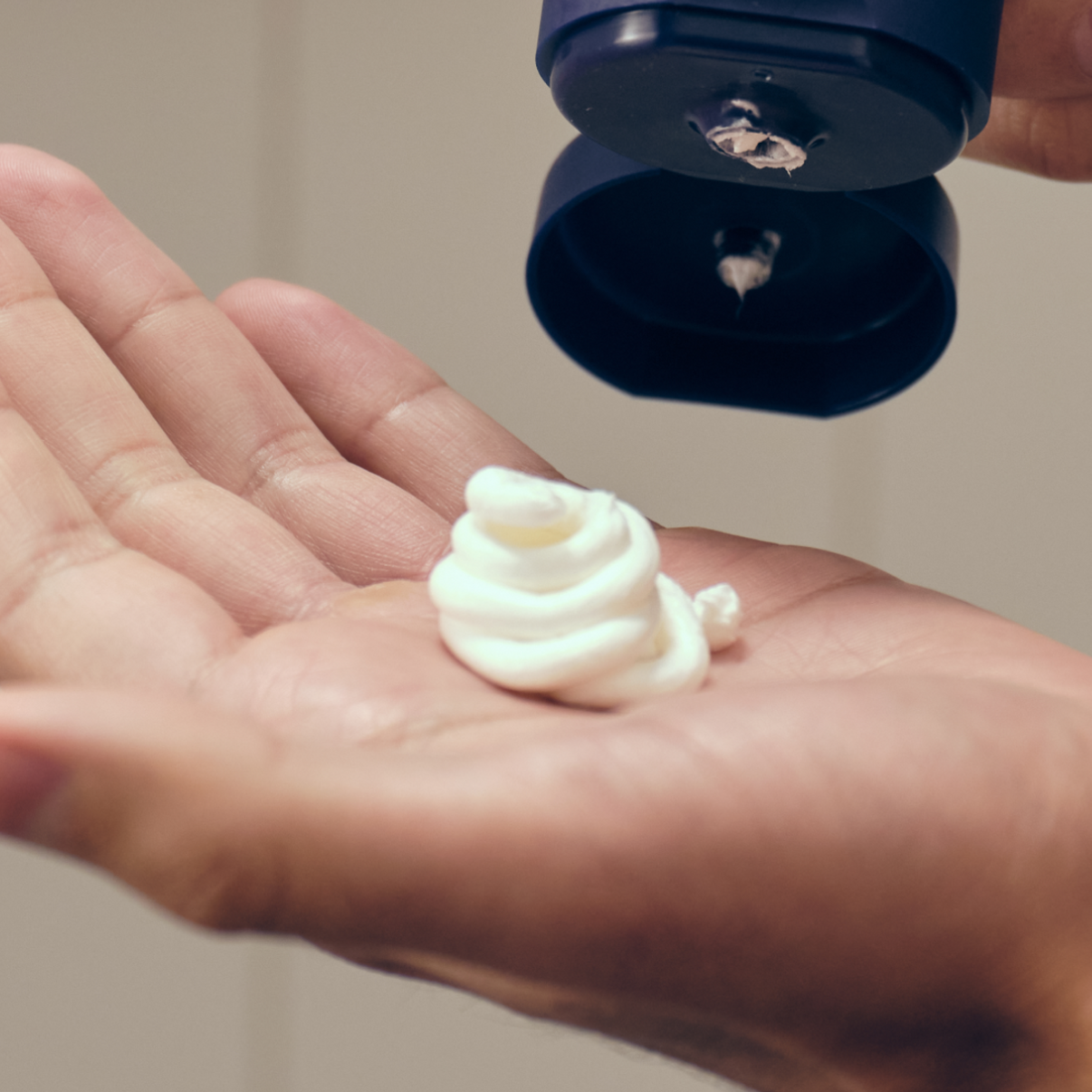 Man holding dollop of post shave cream in hand to show opacity and creamy consistency
