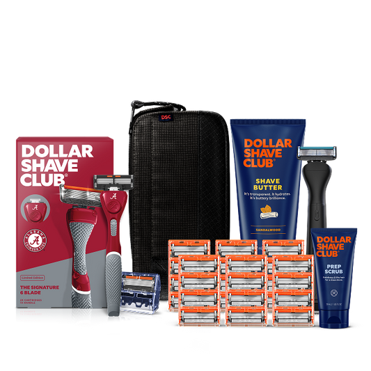 Dollar Shave Club University of Alabama grooming kit on a white background. Includes a crimson razor handle with the Alabama Crimson Tide logo, 24 blades, Shave Butter, Prep Scrub, a black 3-in-1 electric trimmer, and a black traveler case.