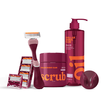 Dollar Shave Club grooming products including a razor, scrub, and shave oil on a black background.
