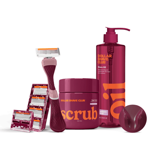 Dollar Shave Club grooming products including a razor, scrub, and shave oil on a black background.