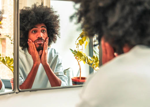 man touching face and looking in a mirror