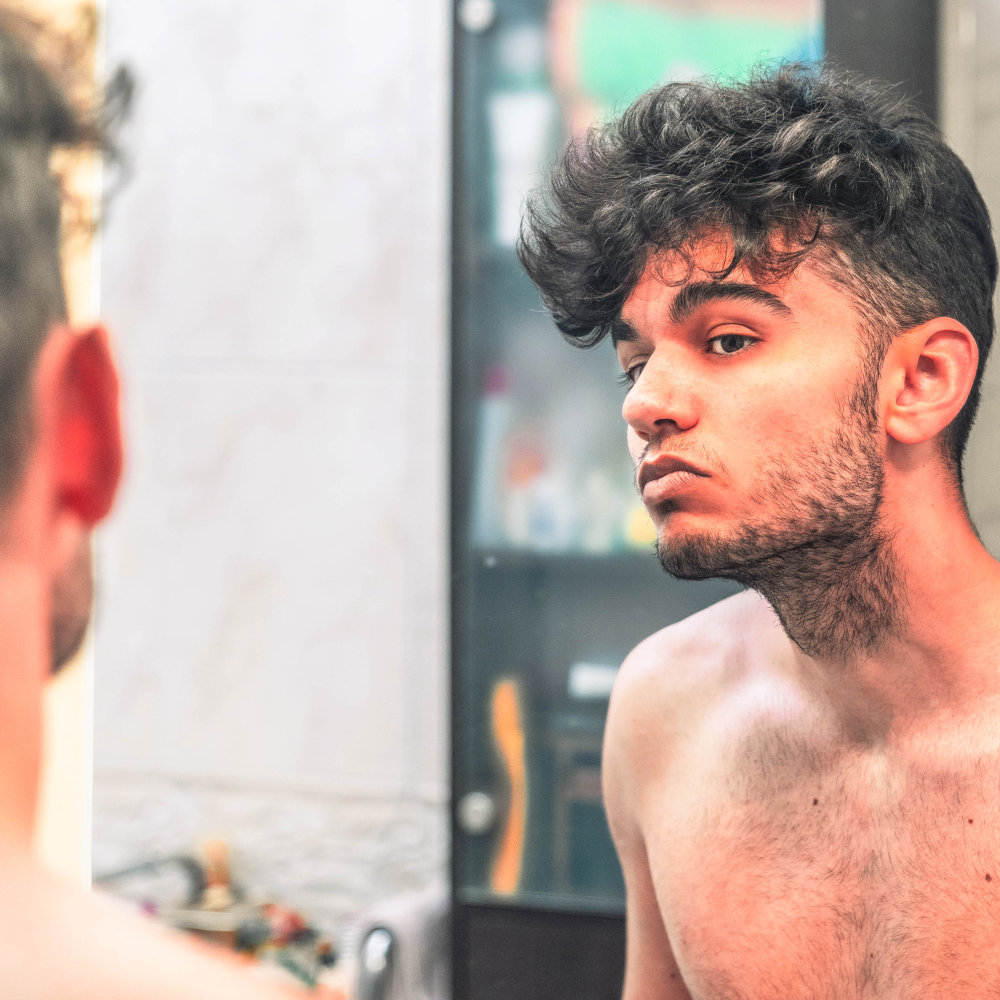 Man looking in mirror at beard before shaving.